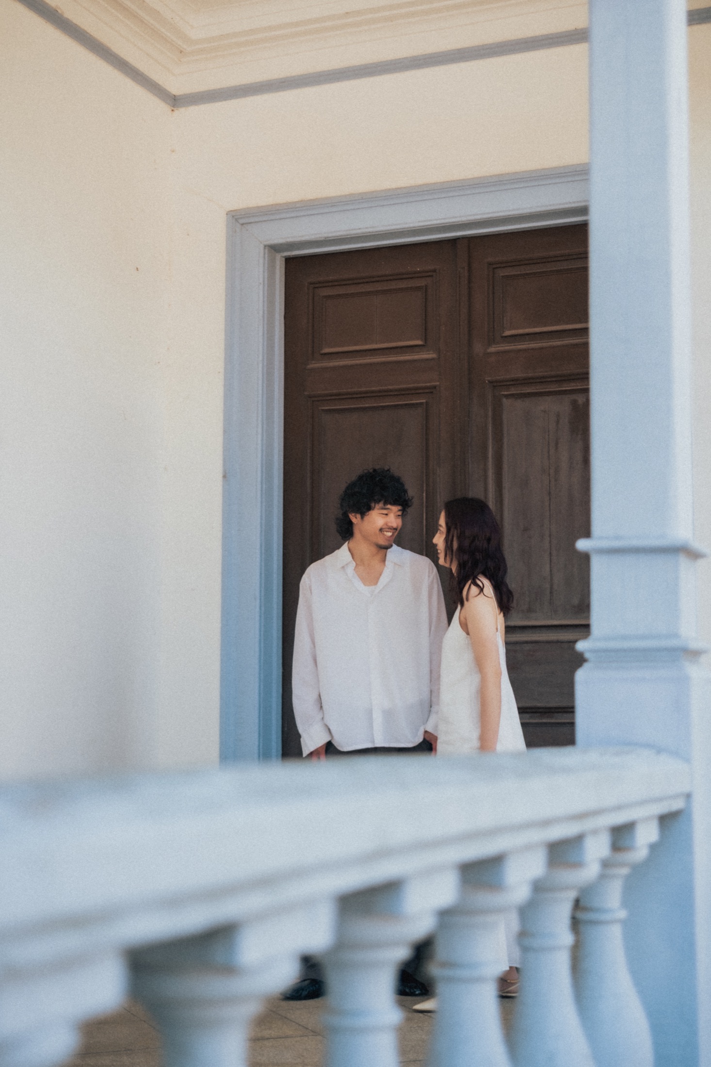 旧学習院初等科正堂のベランダと木の扉の前で向き合うふたり