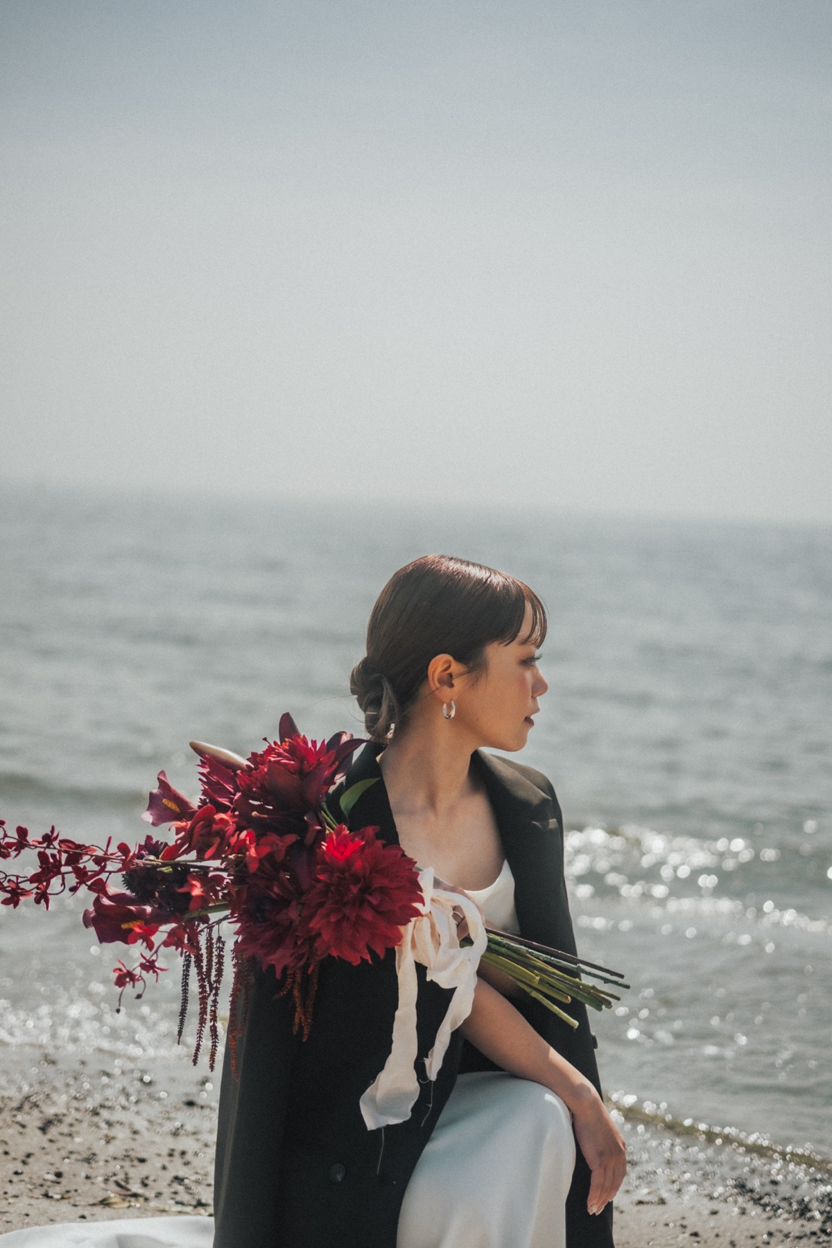 稲毛海浜公園の海辺で赤いブーケを持つ白いドレス姿の新婦