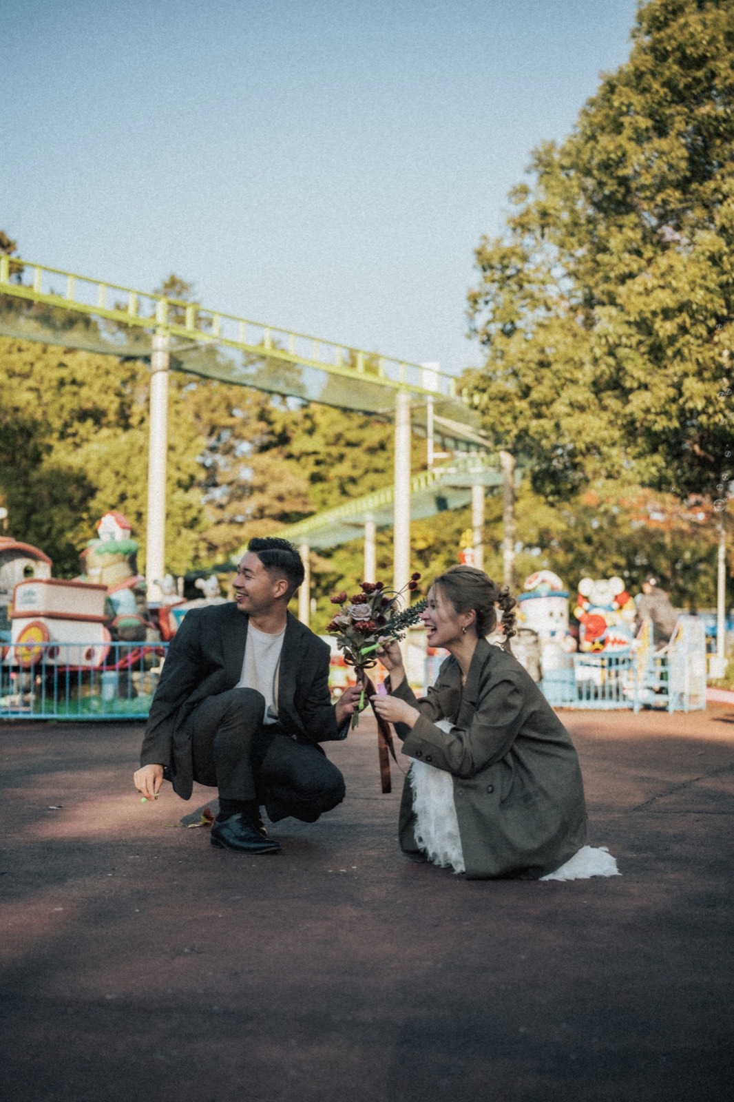 遊園地で肩を寄せるふたりのウェディングフォト